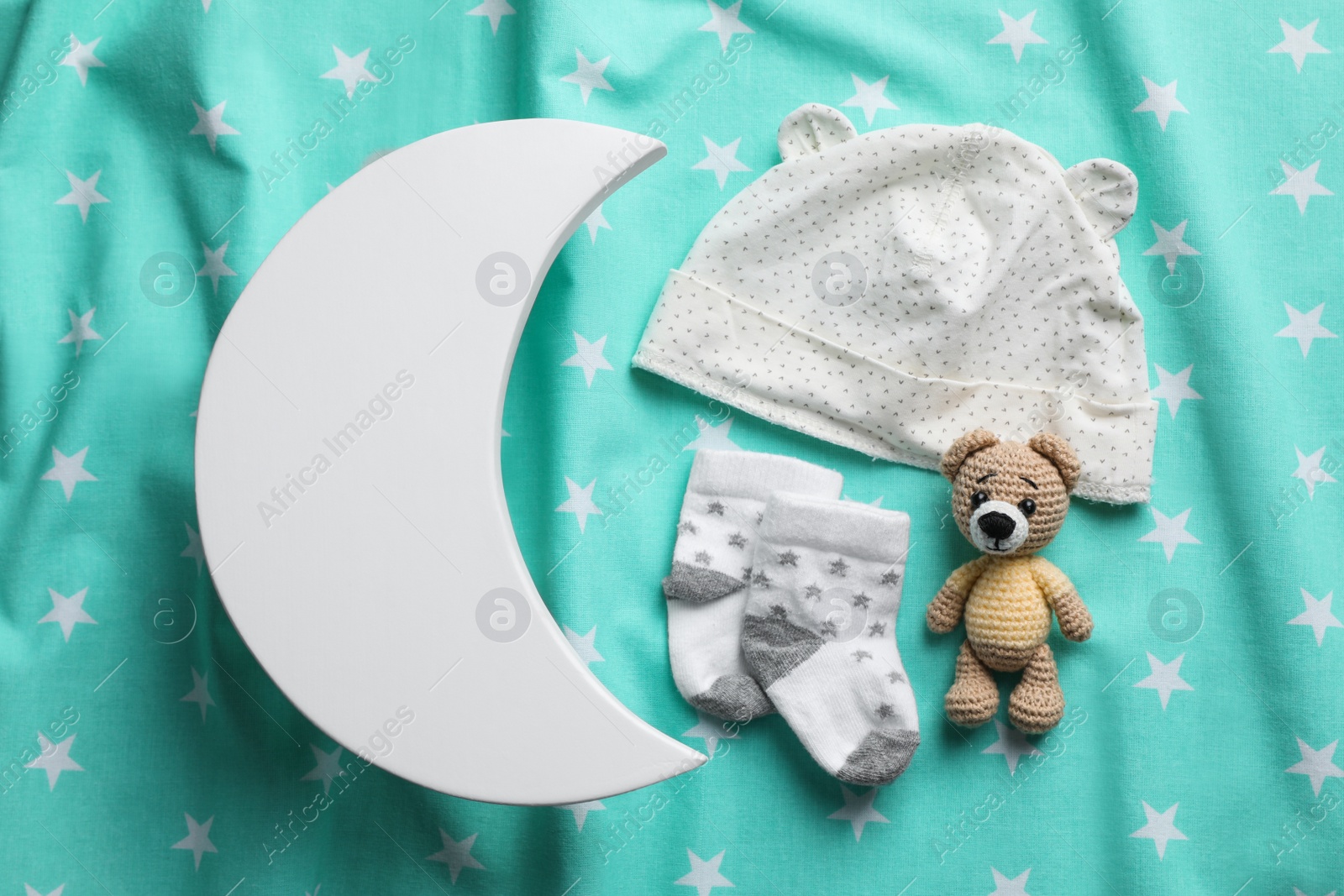 Photo of Flat lay composition with crescent shaped child's night lamp on turquoise fabric