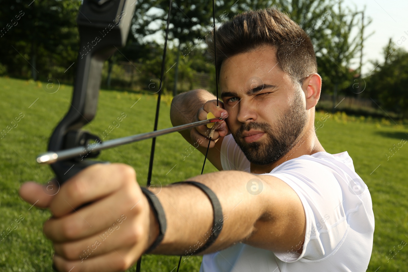 Photo of Man with bow and arrow practicing archery in park