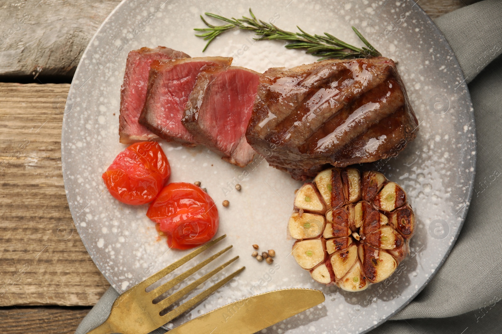 Photo of Delicious grilled beef steak served with spices and tomatoes on table, top view