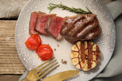 Delicious grilled beef steak served with spices and tomatoes on table, top view