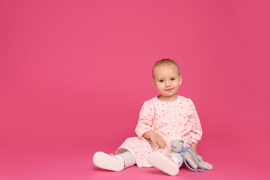 Photo of Cute little child playing with knitted toy on pink background. Space for text