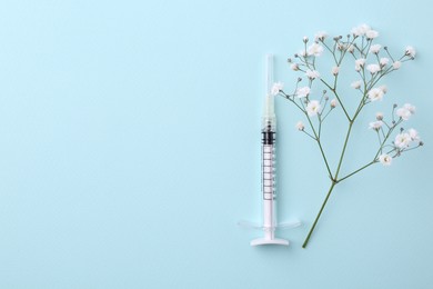 Photo of Cosmetology. Medical syringe and gypsophila on light blue background, flat lay. Space for text