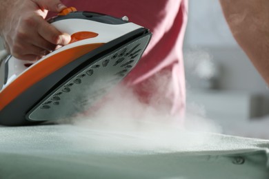 Photo of Man ironing clean shirt at home, closeup