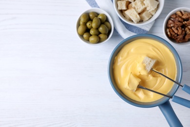 Photo of Flat lay composition with cheese fondue and products on white wooden table, space for text