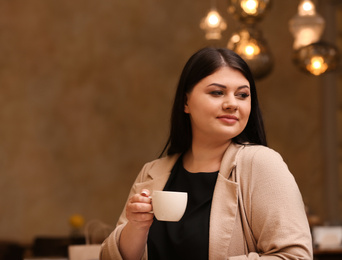 Photo of Beautiful overweight woman in cafe, space for text. Plus size model
