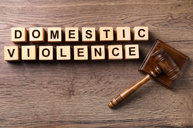 Photo of Wooden cubes with words DOMESTIC VIOLENCE and gavel on table, flat lay