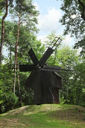 Old wooden windmill on meadow in forest
