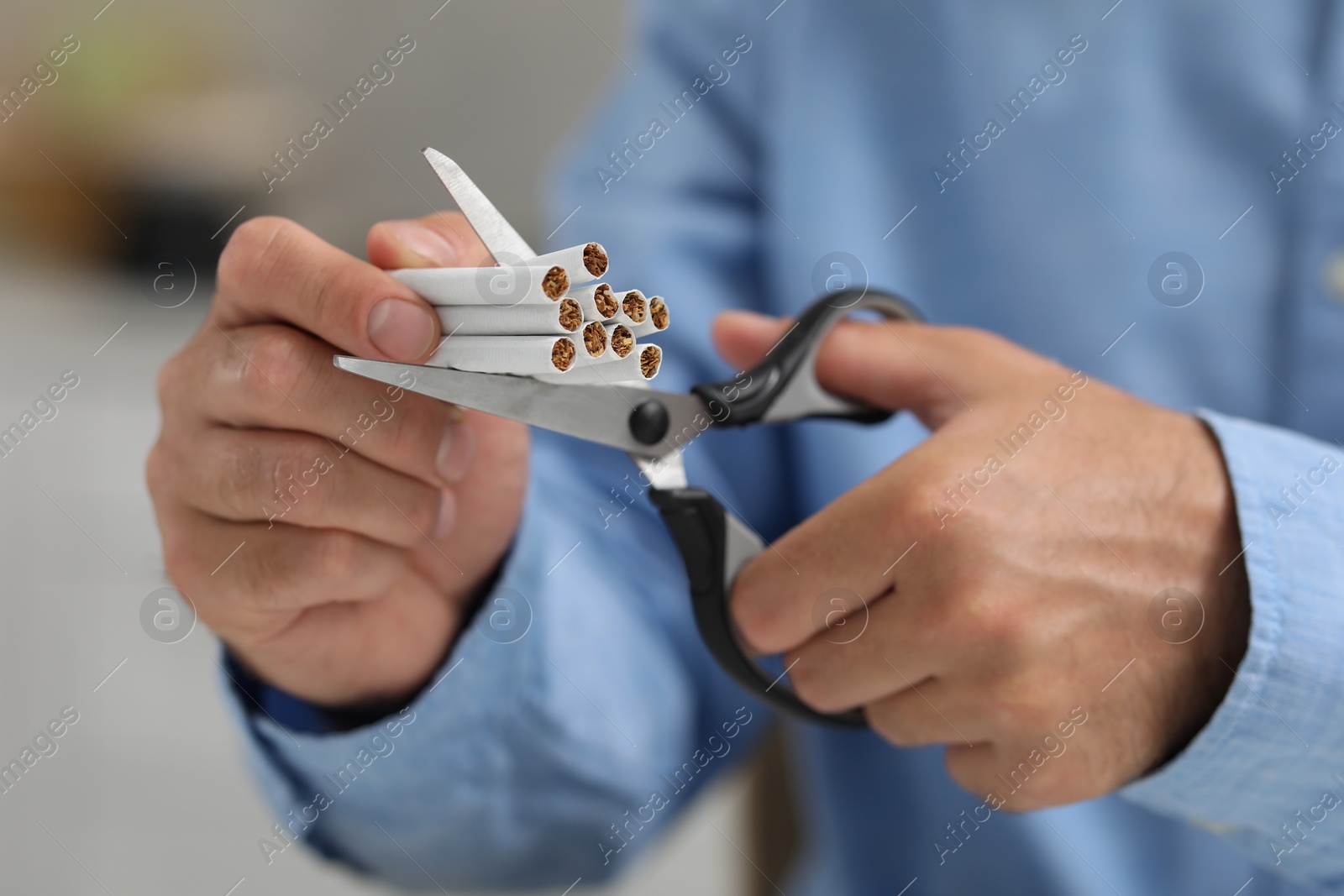 Photo of Stop smoking concept. Man cutting cigarettes on blurred background, closeup