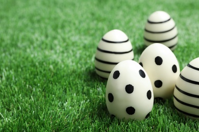 Traditional Easter eggs decorated with black paint on green lawn, space for text