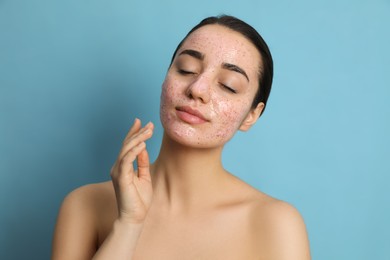 Photo of Woman with pomegranate face mask on light blue background