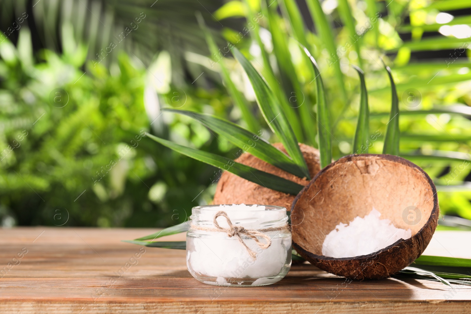 Photo of Composition with natural organic coconut oil on wooden table. Space for text