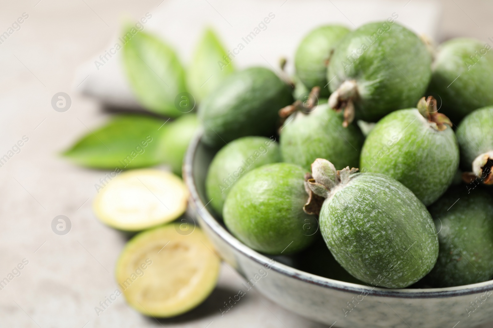 Photo of Fresh green feijoa fruits on light grey table, closeup. Space for text