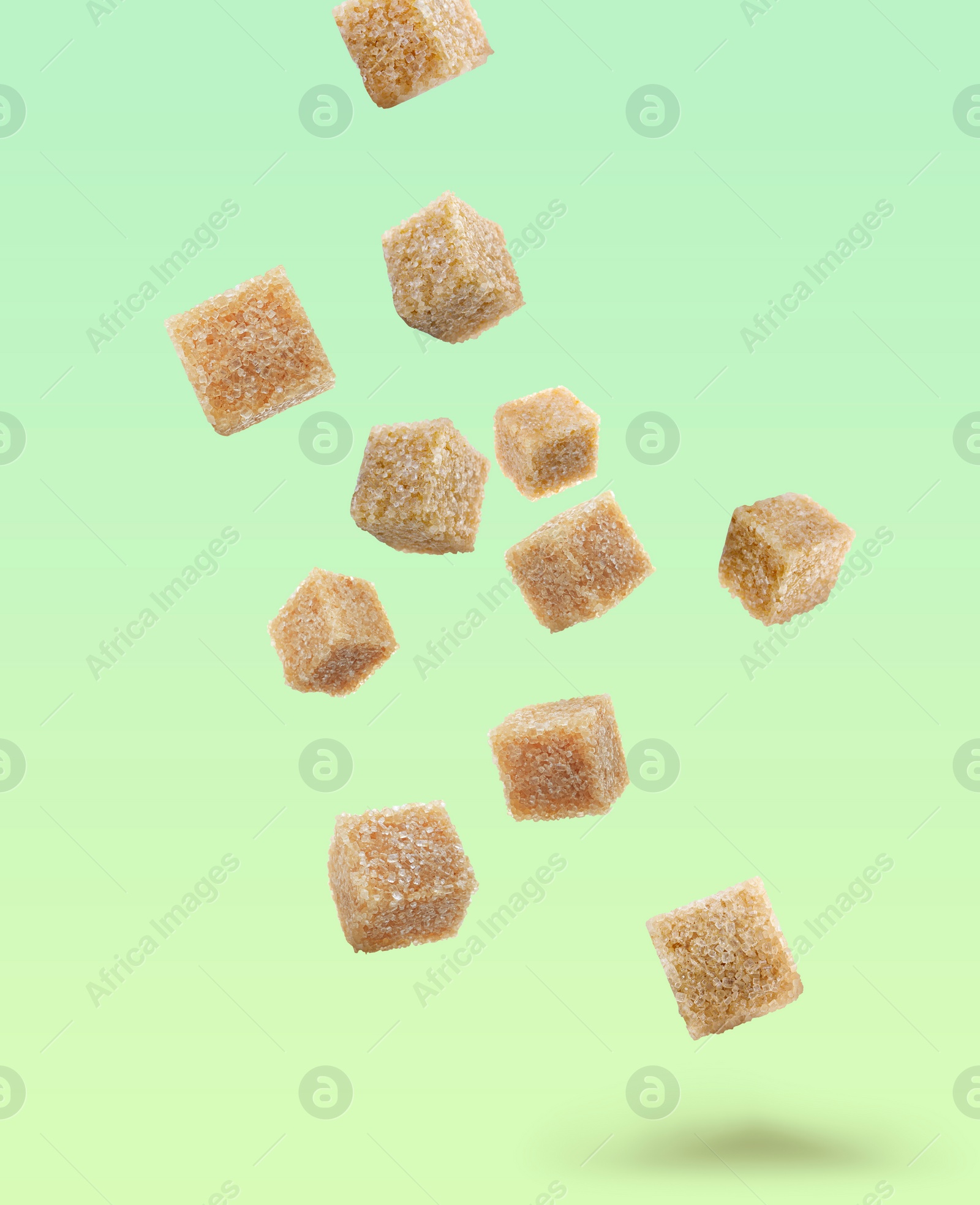 Image of Brown cane sugar cubes falling on color gradient background