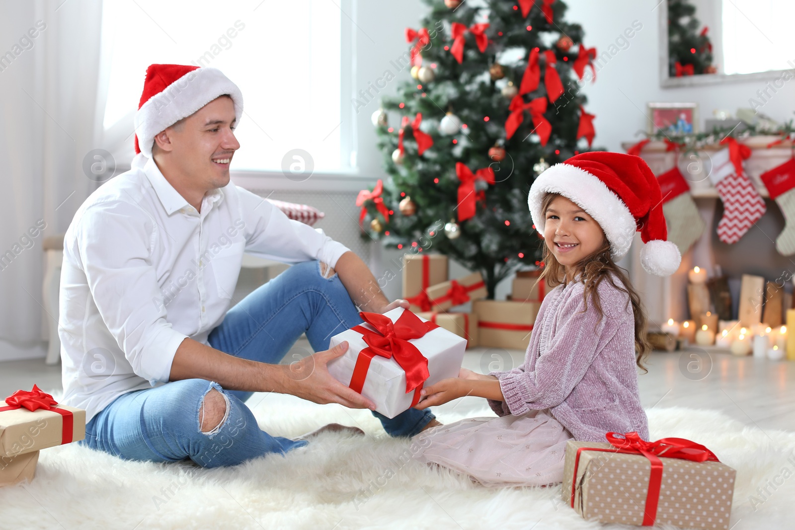 Photo of Father and child in Santa hats with gifts at home. Christmas celebration