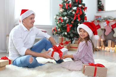 Father and child in Santa hats with gifts at home. Christmas celebration