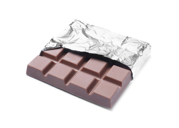 Photo of Delicious milk chocolate bar wrapped in foil isolated on white