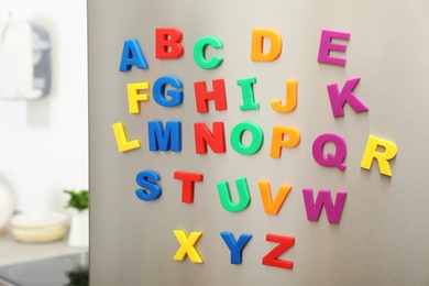 Photo of Colorful magnetic letters on refrigerator door indoors