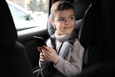 Photo of Cute little boy listening to audiobook in car