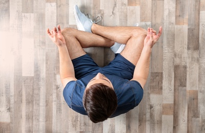 Photo of Young man sitting on floor and practicing zen yoga, top view