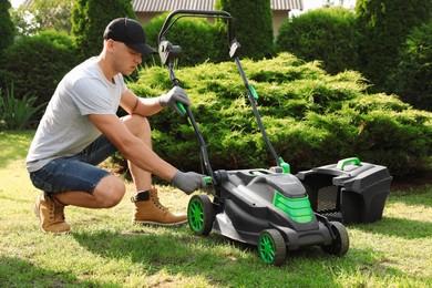 Young man fixing lawn mower in garden