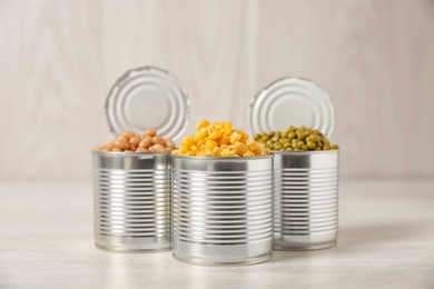 Photo of Open tin cans with conserved vegetables on light table