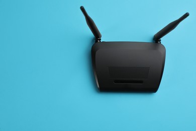 Photo of Modern Wi-Fi router on light blue background, top view. Space for text