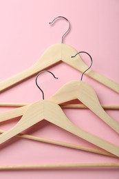 Wooden hangers on pink background, top view