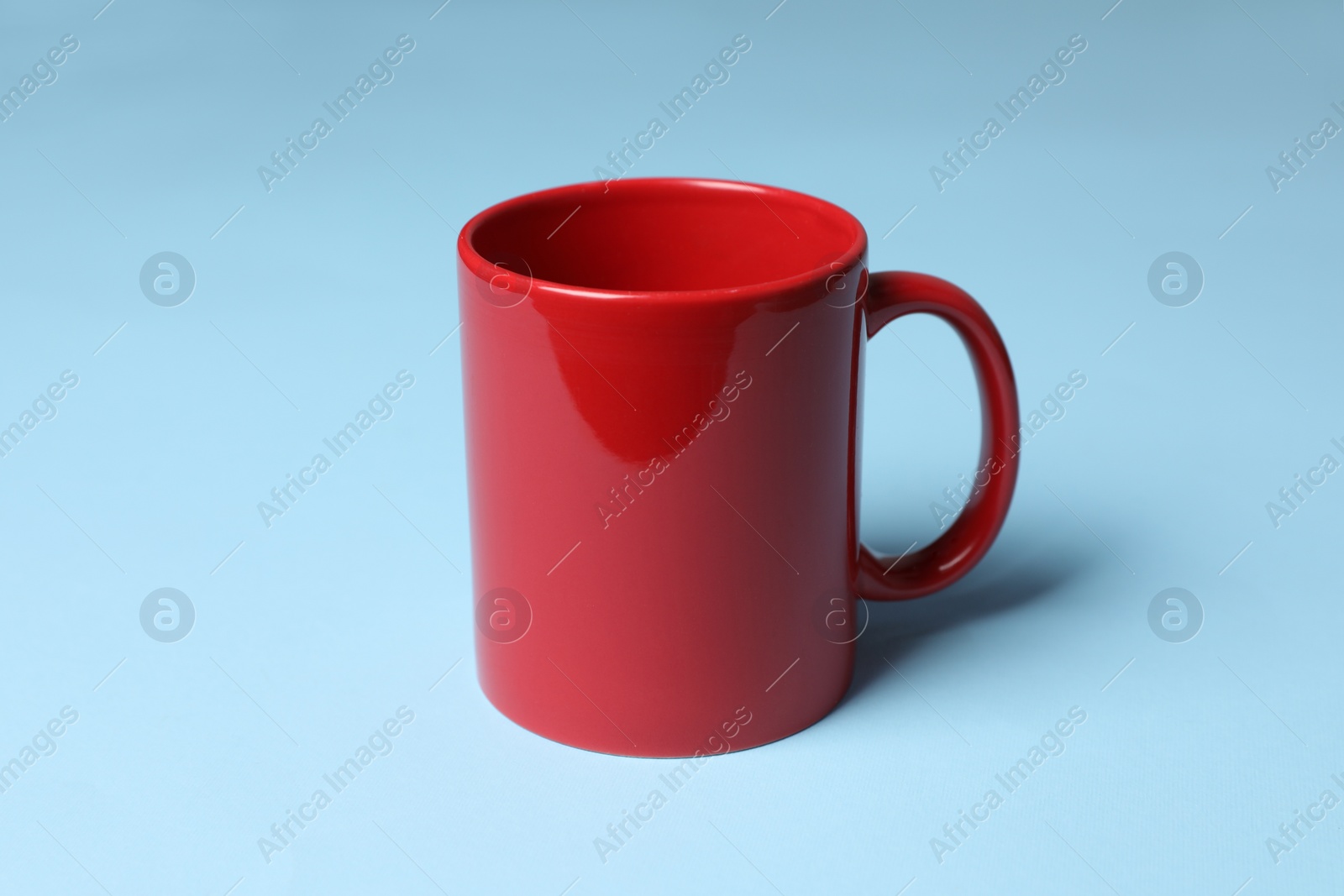One red ceramic mug on light blue background Photo of One red ceramic mug on light blue background