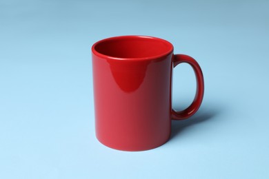 Photo of One red ceramic mug on light blue background