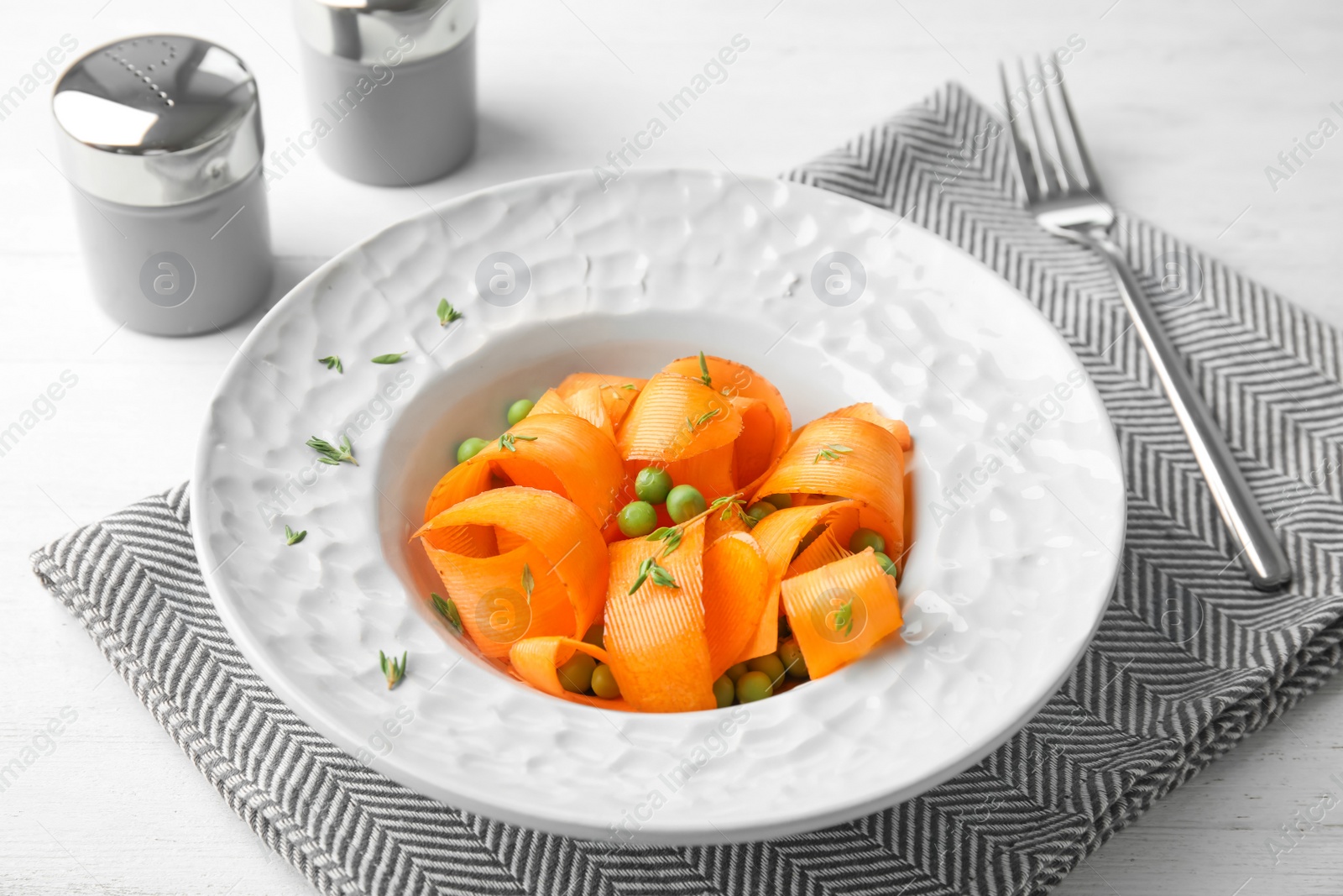 Photo of Tasty salad with fresh carrot in plate on table