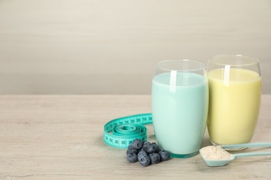 Photo of Tasty shakes with blueberries, measuring tape and powder on wooden table, space for text. Weight loss