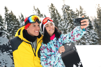 Photo of Couple taking selfie on snowy hill. Winter vacation