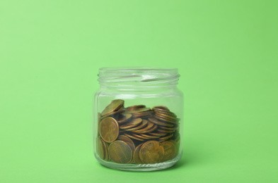 Photo of Glass jar with coins on light green background