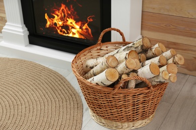 Firewood in wicker basket near fireplace indoors