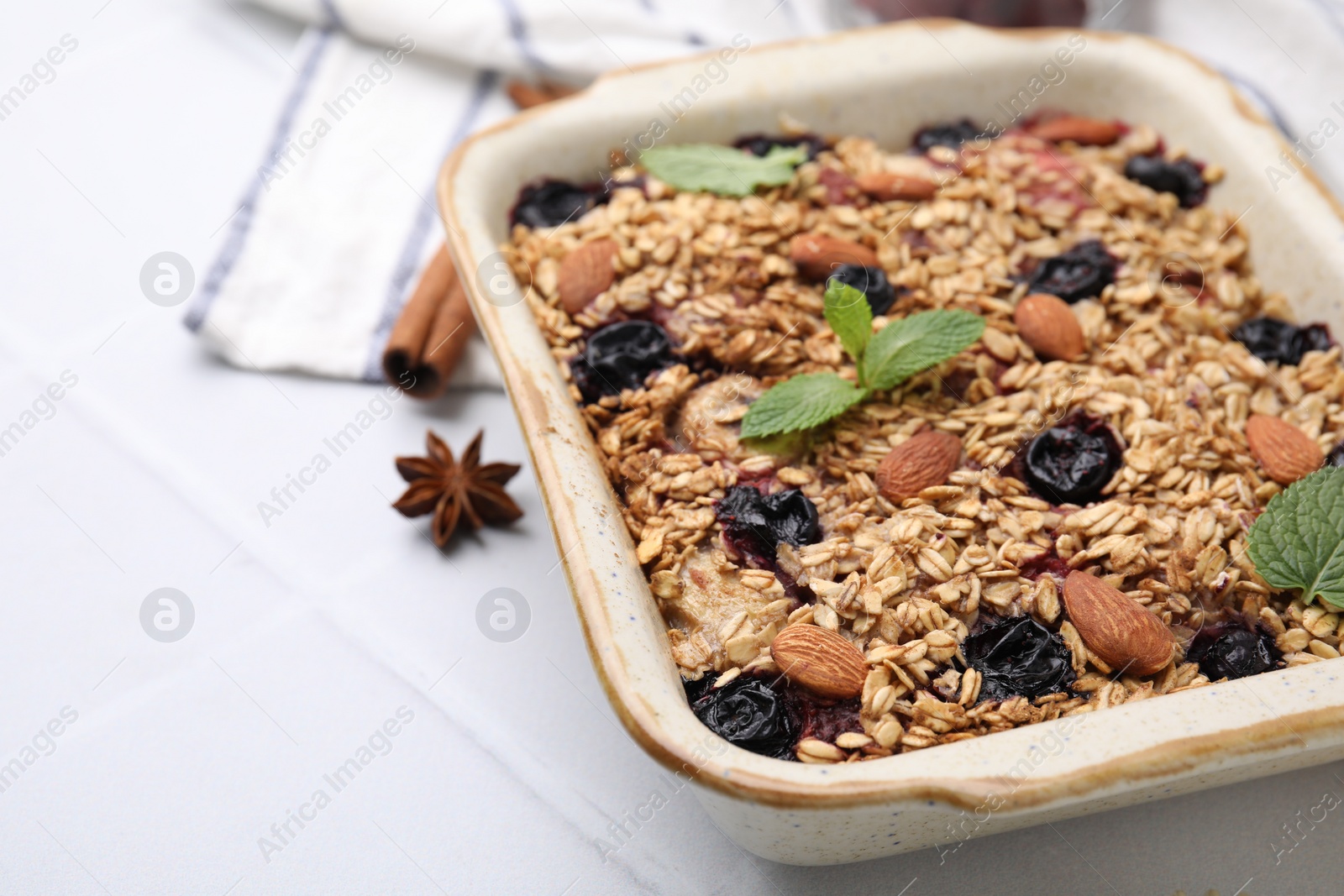 Photo of Tasty baked oatmeal with berries and almonds on white table, closeup. Space for text
