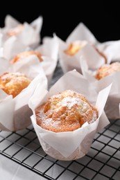 Delicious muffins with powdered sugar on light table, closeup