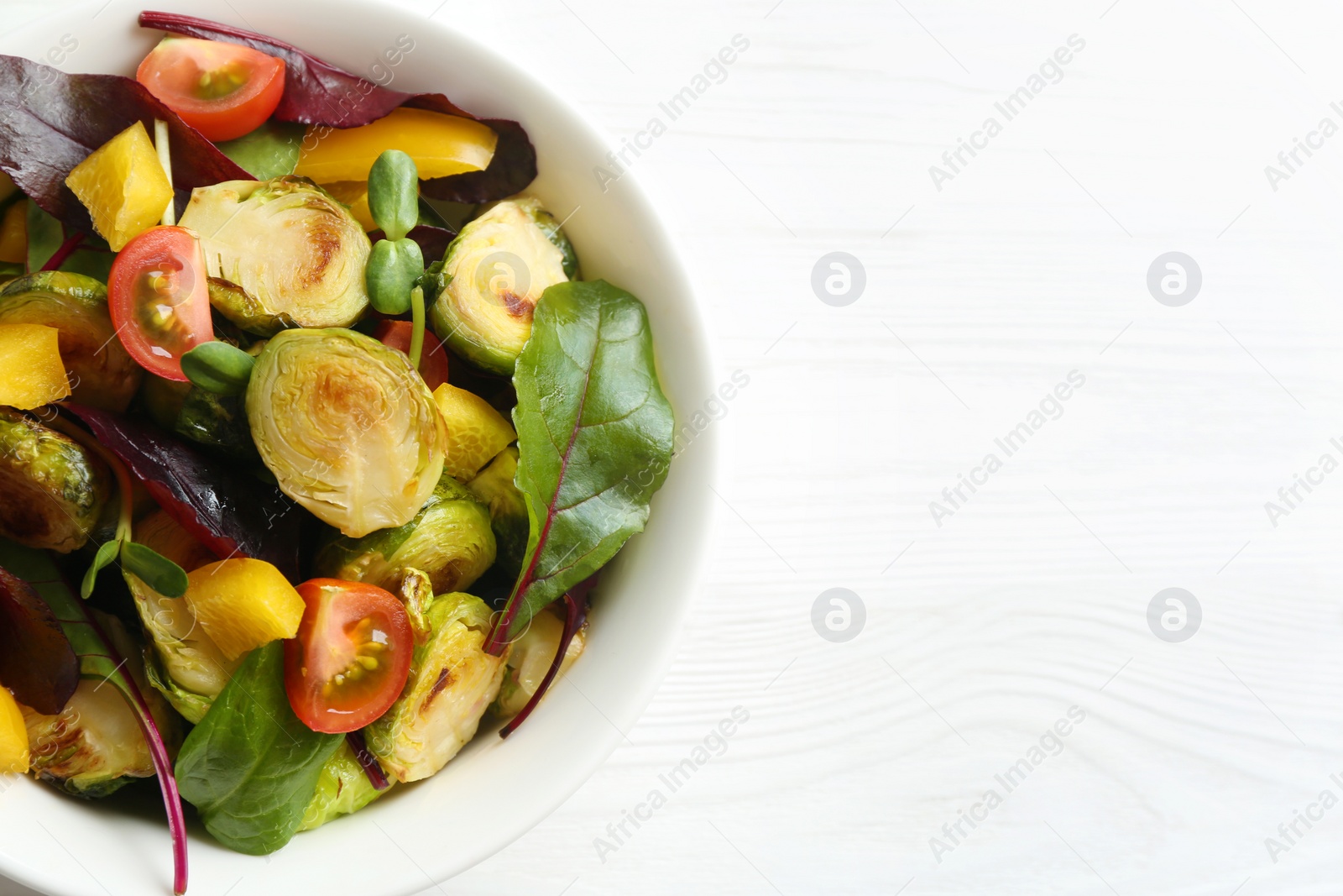 Photo of Delicious salad with roasted Brussels sprouts on white wooden table, top view. Space for text