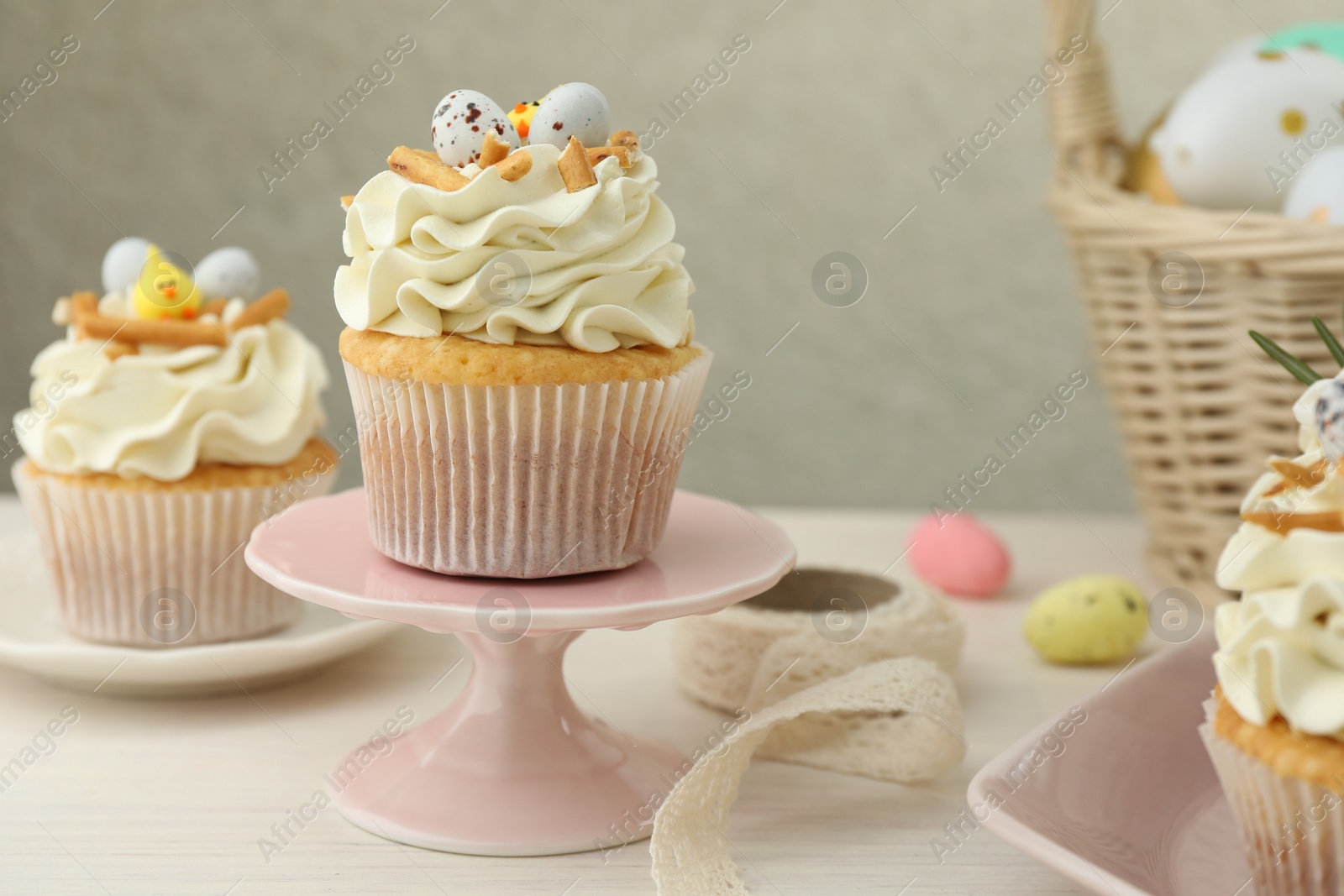 Photo of Tasty Easter cupcakes with vanilla cream on light wooden table