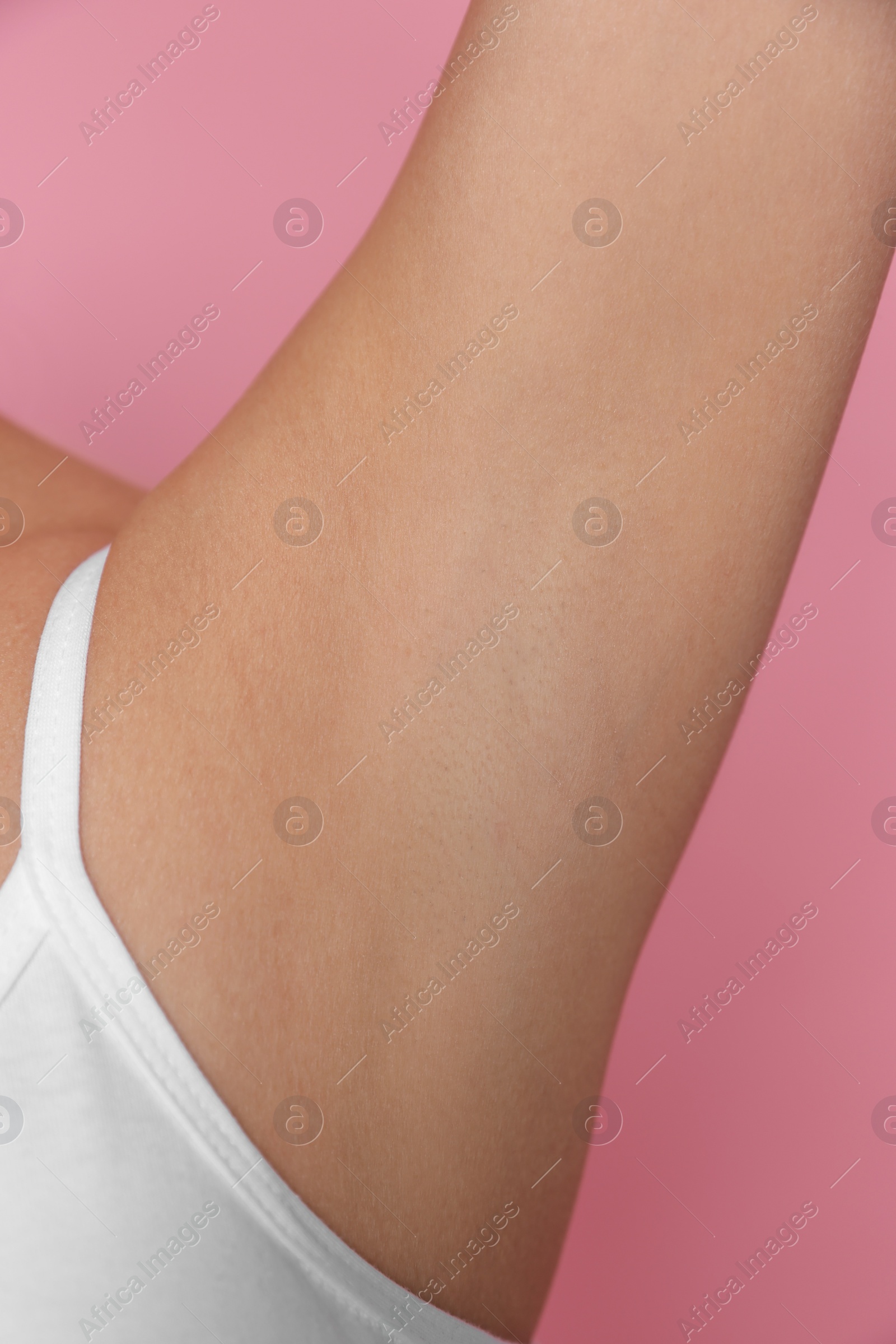 Photo of Young woman showing smooth skin after epilation on pink background, closeup