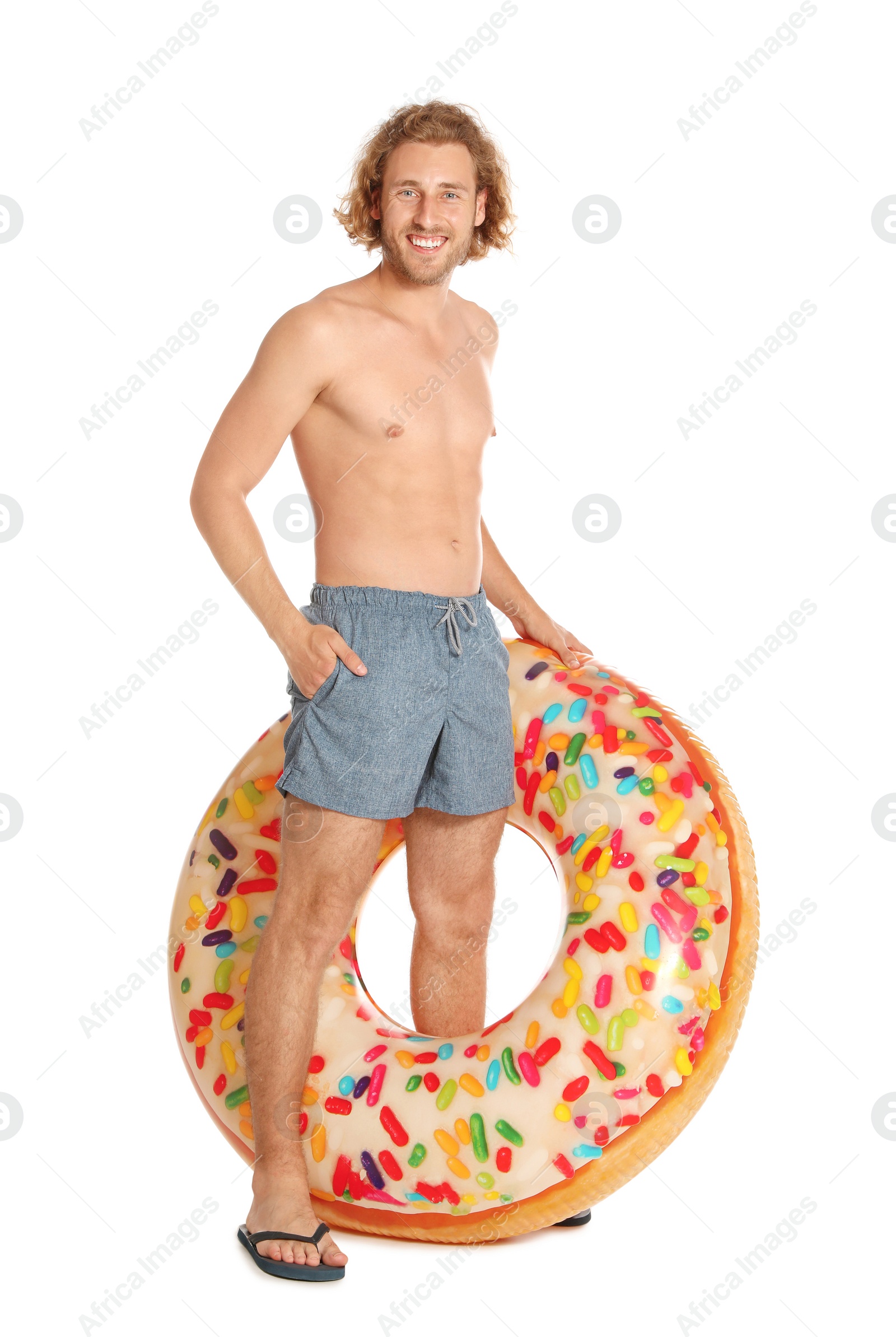 Photo of Attractive young man in swimwear with doughnut inflatable ring on white background