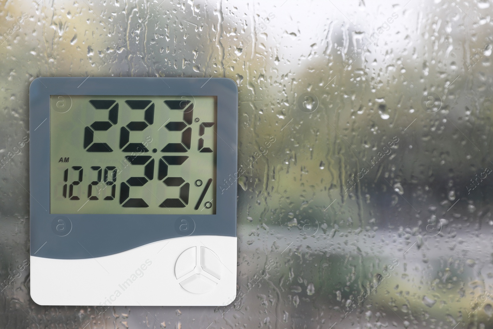 Image of Digital hygrometer with thermometer on glass with water drops. Space for text