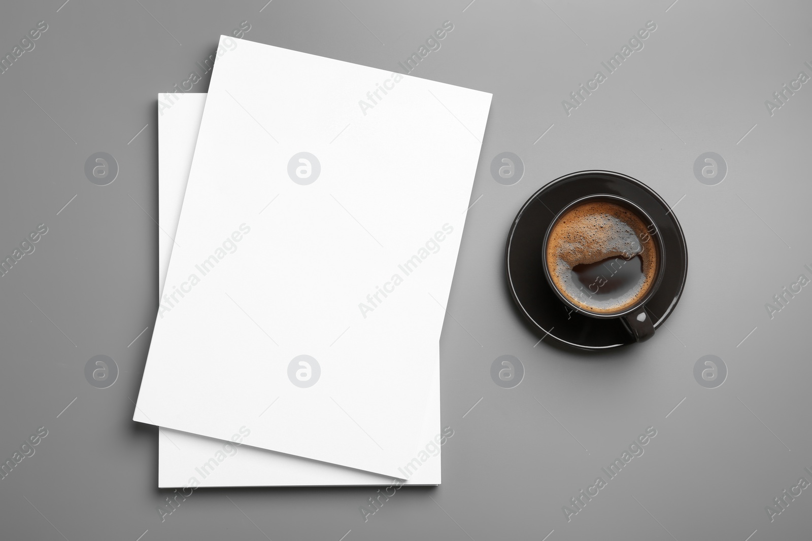 Photo of Blank paper sheets for brochure and cup of coffee on grey background, flat lay. Mock up