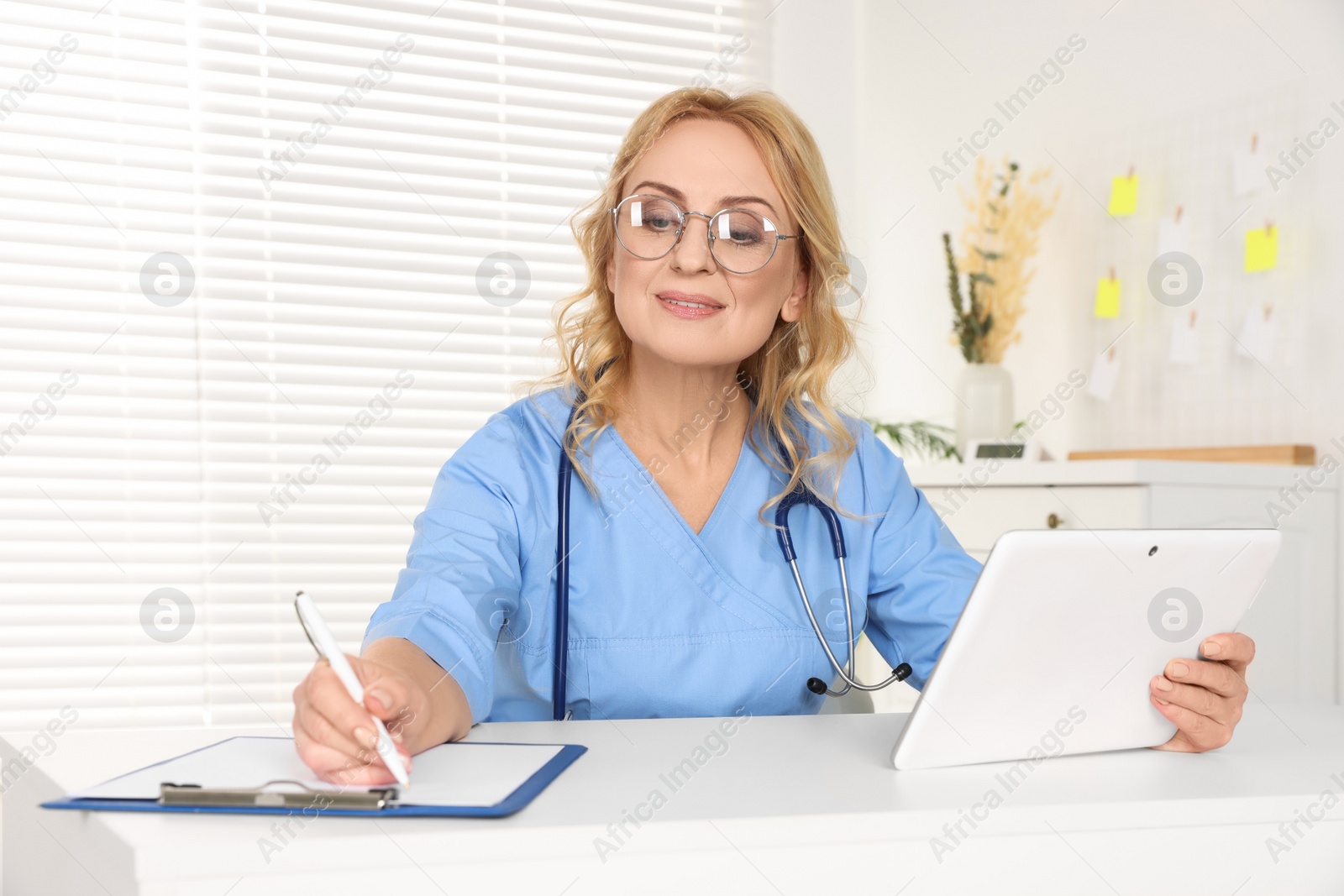 Photo of Doctor with glasses and tablet consulting patient in clinic. Online medicine concept