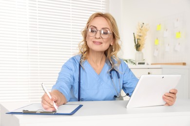 Doctor with glasses and tablet consulting patient in clinic. Online medicine concept