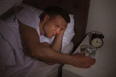 Young man with terrible headache want to take pill at night