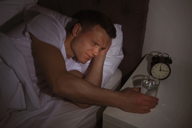 Photo of Young man with terrible headache want to take pill at night