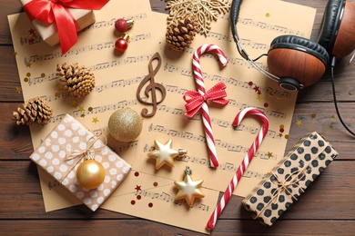 Photo of Flat lay composition with Christmas decorations, music sheets and headphones on wooden background