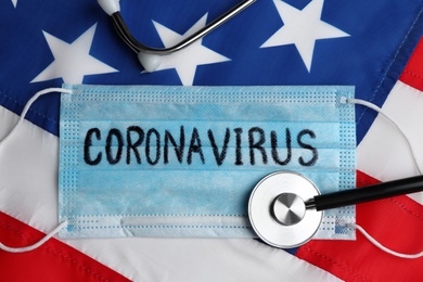 Medical mask and stethoscope on American flag, flat lay. Coronavirus pandemic in USA