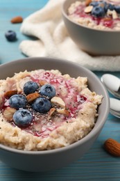 Photo of Tasty oatmeal porridge with toppings on light blue wooden table, closeup