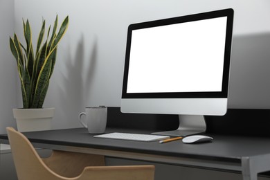 Photo of Modern computer with blank screen on black table indoors. Mockup for design